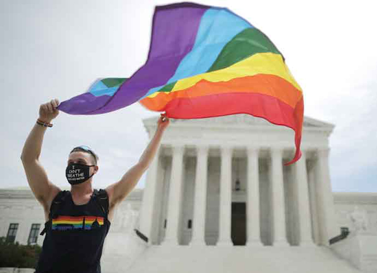 WASHINGTON, DC - JUNE 15: Joseph Fons holding a Pride Flag in front of the U.S. Supreme Court building after the court ruled that LGBTQ people can not be disciplined or fired based on their sexual orientation, Washington, DC, June 15, 2020. With Chief Justice John Roberts and Justice Neil Gorsuch joining the Democratic appointees, the court ruled 6-3 that the Civil Rights Act of 1964 bans bias based on sexual orientation or gender identity. Fons is wearing a Black Lives Matter mask with the words