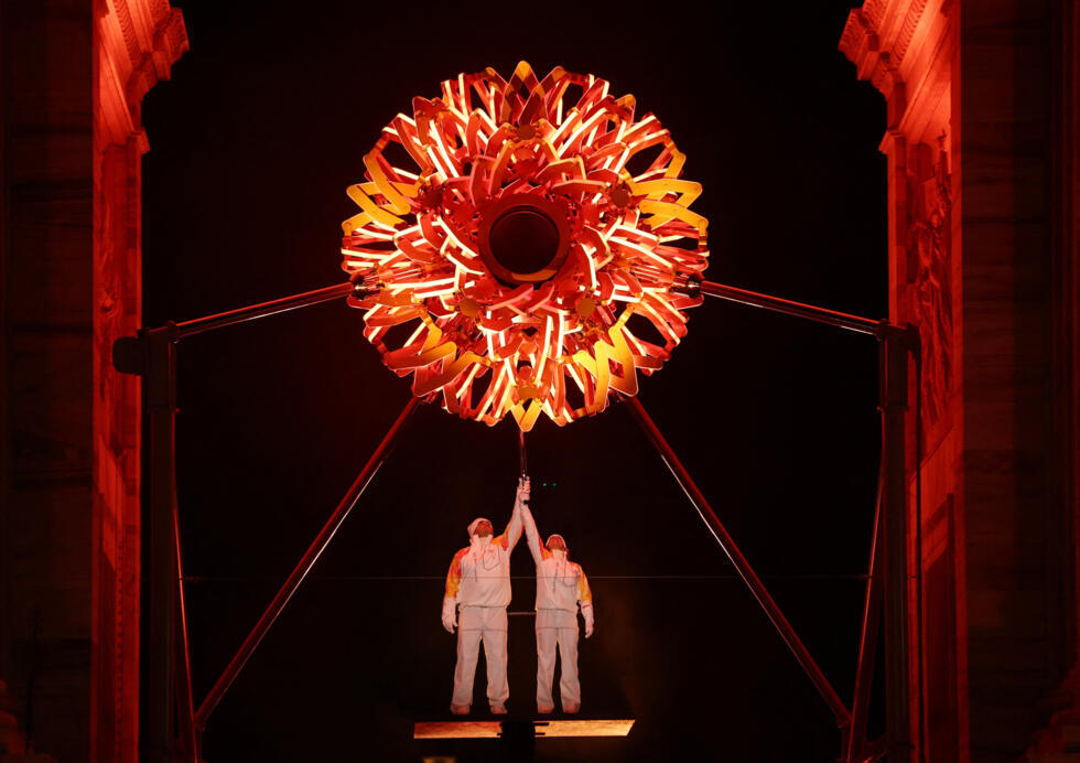 The Olympic cauldron is lit by Alberto Tomba and Deborah Compagnoni.