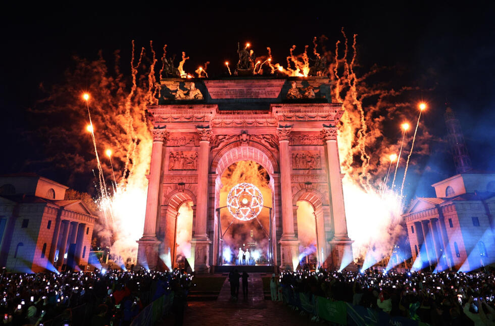the Olympic cauldron under the Arco della Pace in Milan is lit by Alberto Tomba and Deborah Compagnoni.