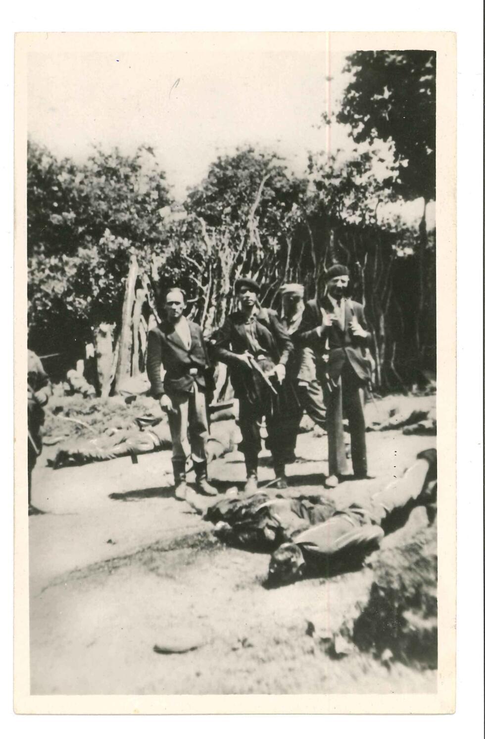 French agents working for the German intelligence service Abwehr pose for a photo next to the bodies of the resistance fighters they killed in the village of Plumelec, in Brittany, on July 12, 1944