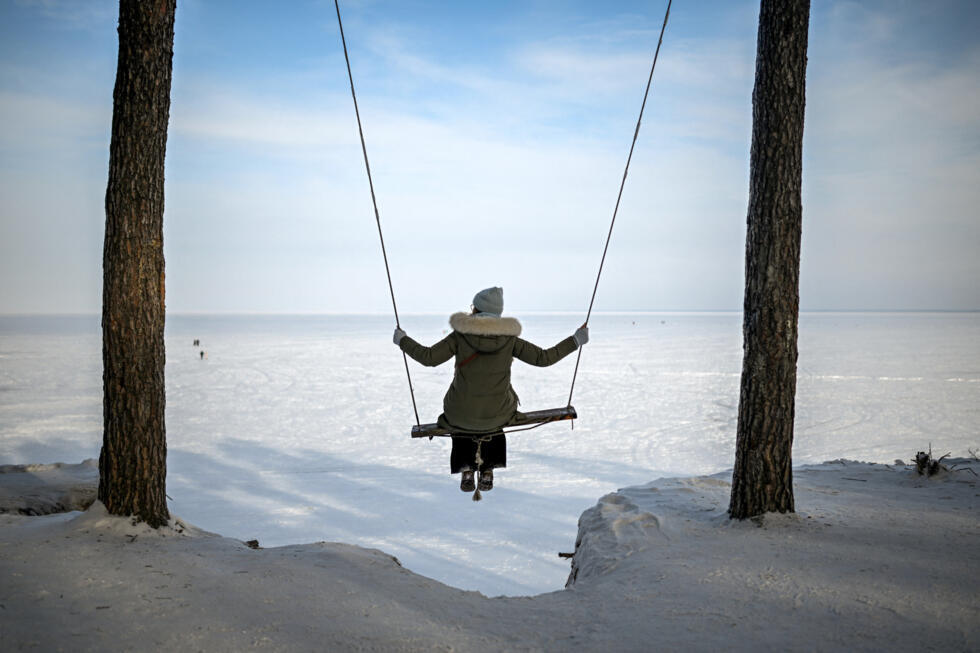 A woman rides a swing above the frozen Kyiv Reservoir, also known as the Kyiv Sea, in Lyutizh.