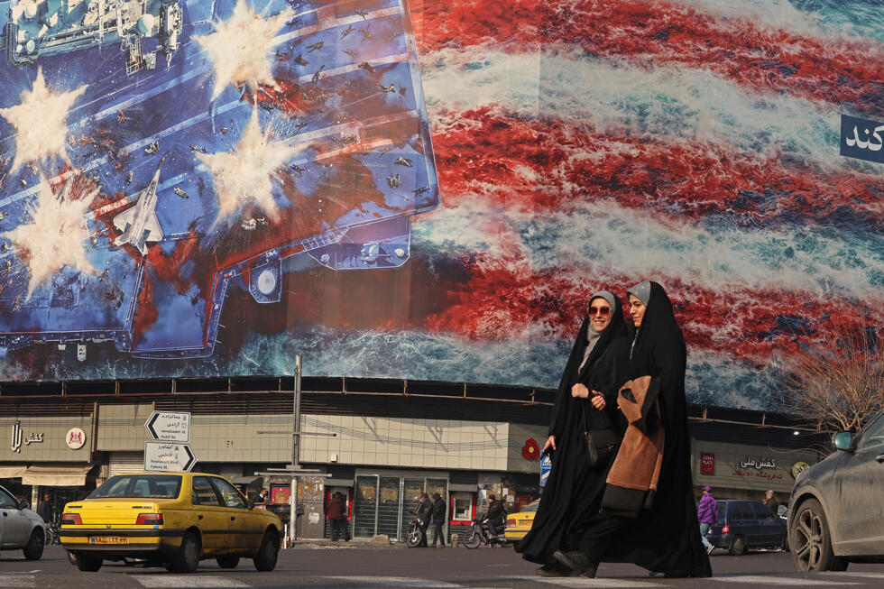 Iranian women walk past an anti-US billboard installed on a building at the Enqelab Square in Tehran.