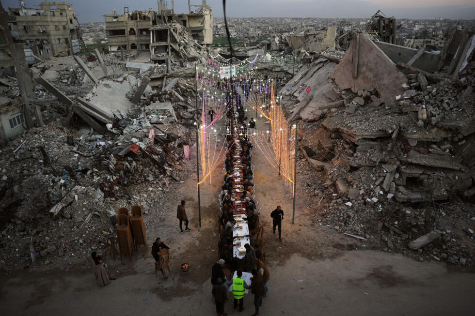 Palestinians sit at a long table amid the rubble of destroyed buildings as they gather for iftar, the fast-breaking meal, during the Muslim holy month of Ramadan in Khan Younis, on Feb 19, 2026