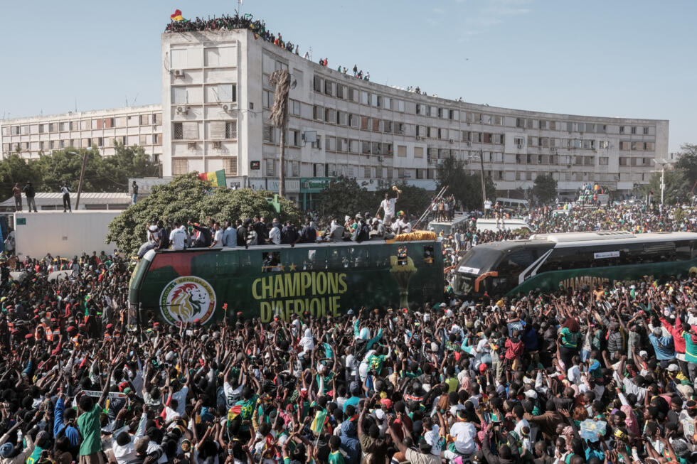 Supporters cheer as Senegal's football players ride on a bus during a trophy parade in the streets of Dakar on January 20, 2026, a day after their dramatic final victory at the Africa Cup of Nations.