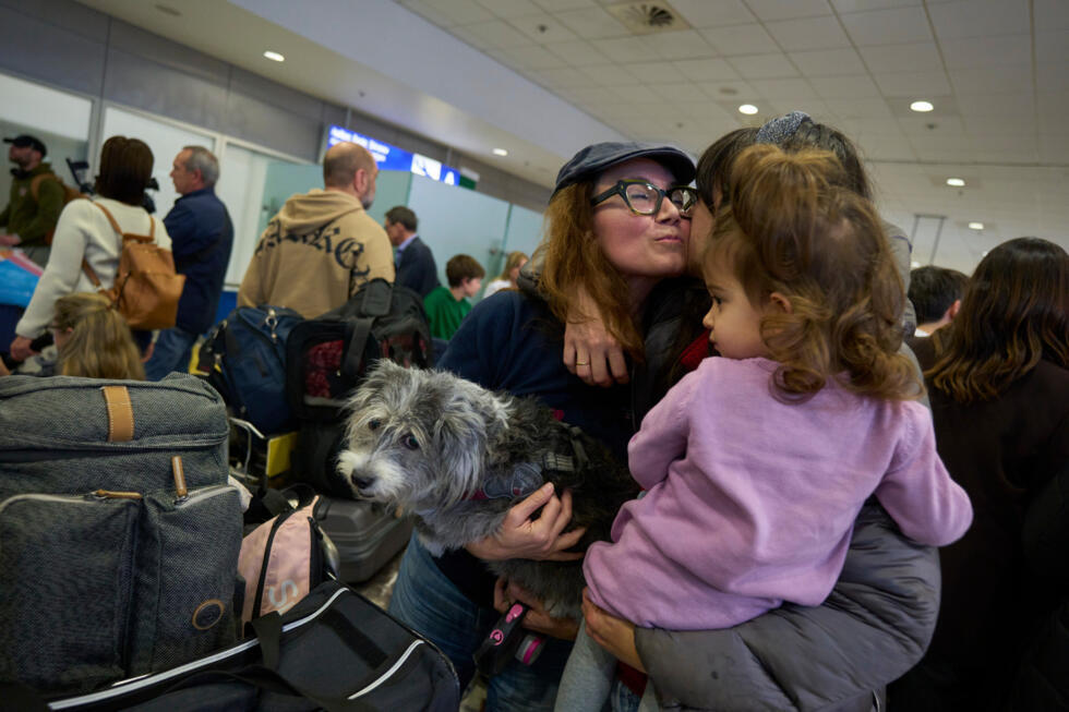 A repatriated Greek woman with her dog hugs relatives during their arrival at Athens International Airport