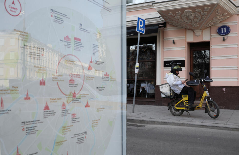 A delivery courier checks his mobile phone in central Moscow, on March 17, 2026