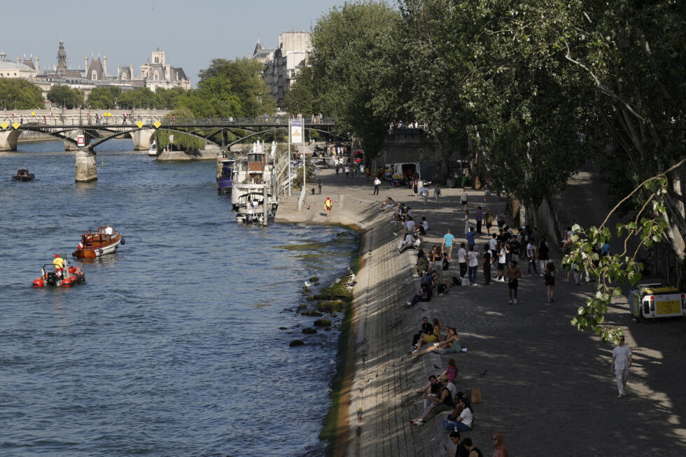 People walk and rest on the Seine River banks in Paris.
