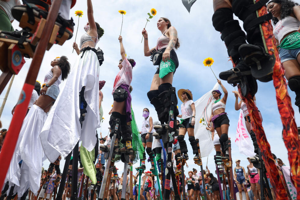 Women on stilts, from the collective Gigantes na Luta, hold plastic sunflowers in the air during a march marking International Women's Day in Rio de Janeiro, Brazil March 8, 2026.