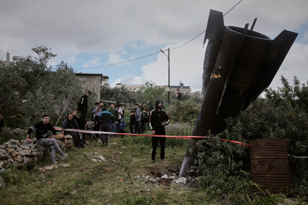Palestinians gather around the wreckage of an Iranian missile that landed in the West Bank village of Kifl Haris.