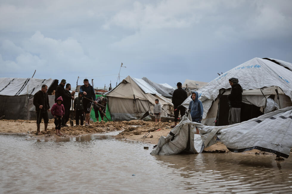 Palestinians walk through a flooded area in a temporary tent camp after heavy rainfall in Gaza City.