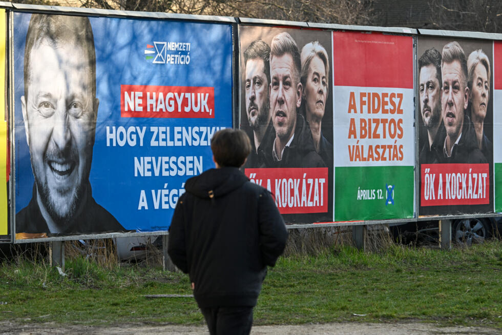A pedestrian walks past a pro-government billboards featuring a portrait of Ukrainian President Volodymyr Zelensky (L), with the text reading, 'Let's not let Zelensky have the last laugh, and another