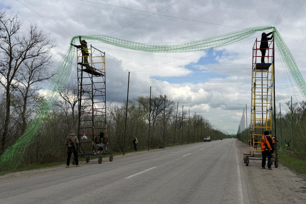 Ukrainian servicemen cover the road with a net to protect vehicles from drone attacks in the Zaporizhzhia region.