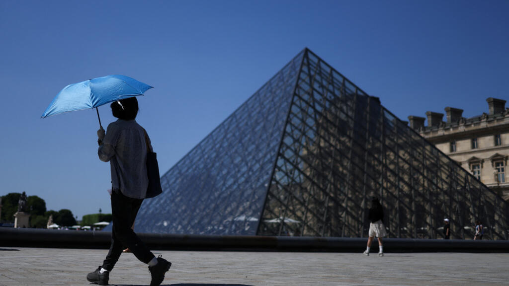 Una persona se protege del sol con un paraguas frente al Louvre durante una ola de calor en París, Francia, el 27 de mayo de 2026.