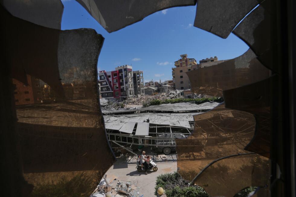 Buildings damaged by Israeli strikes are seen through shattered glass from the Jabal Amel Hospital in the southern port city of Tyre, Lebanon on June 18, 2026 